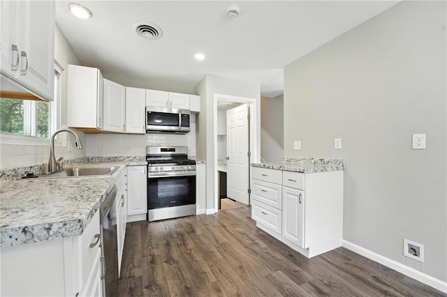 4916 N Manchester Ave, Kansas City, MO 64119 - kitchen with stainless steel appliances, dark wood-style flooring, white cabinets, recessed lighting, and light stone counters