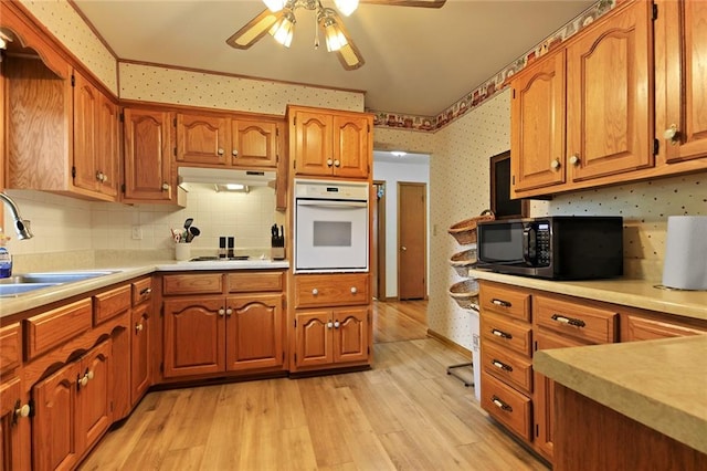 904 Leone Ave, Sedalia, MO 65301 - kitchen featuring oven, under cabinet range hood, wallpapered walls, and brown cabinets