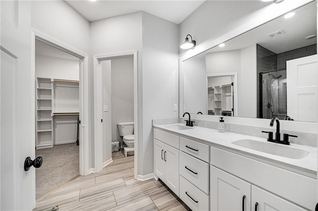 1296 NW Lindenwood Dr, Grain Valley, MO 64029 - full bathroom featuring a spacious closet, double vanity, a shower stall, recessed lighting, and wood finish floors