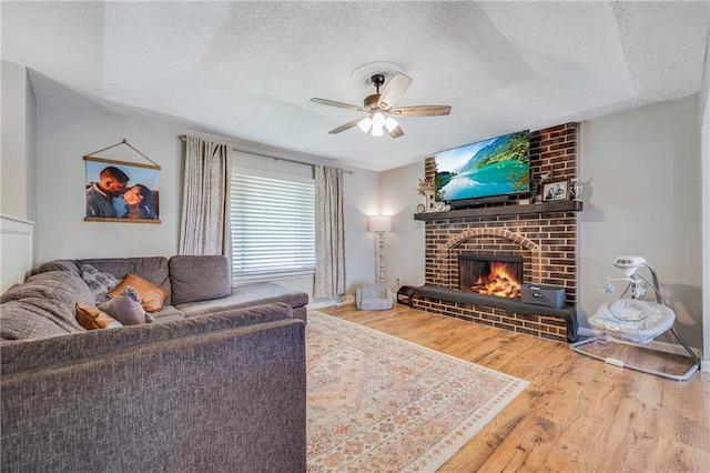 4252 SE Valleyview Ln, Holt, MO 64048 - living room with a textured ceiling, a ceiling fan, wood finished floors, and a fireplace