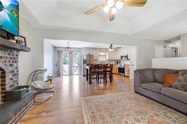 4252 SE Valleyview Ln, Holt, MO 64048 - living room with ceiling fan, light wood finished floors, a fireplace, and a tray ceiling