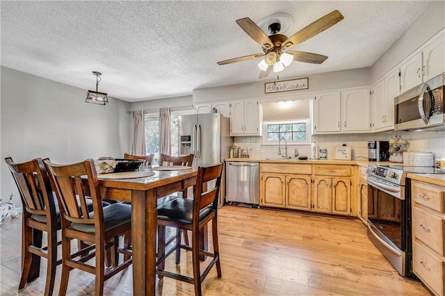 4252 SE Valleyview Ln, Holt, MO 64048 - kitchen featuring stainless steel appliances, light countertops, a textured ceiling, light wood-type flooring, and backsplash