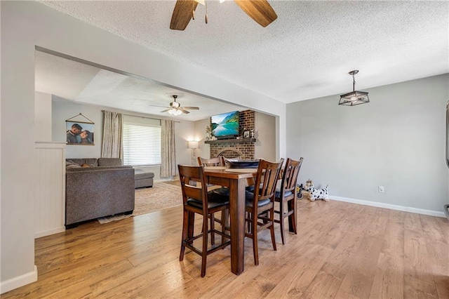 4252 SE Valleyview Ln, Holt, MO 64048 - dining area with a ceiling fan, a textured ceiling, light wood finished floors, and a fireplace