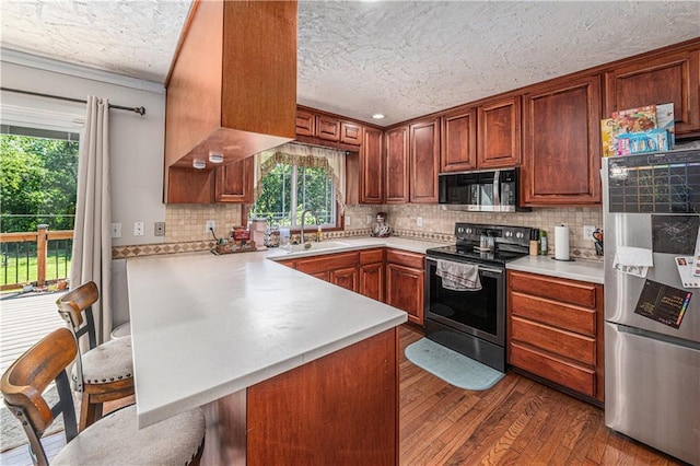 2518 Arrowhead Rd, Topeka, KS 66614 - kitchen featuring appliances with stainless steel finishes, a textured ceiling, a peninsula, healthy amount of natural light, and light countertops