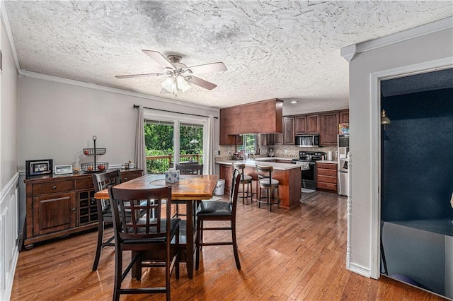 2518 Arrowhead Rd, Topeka, KS 66614 - dining area featuring light wood-type flooring, a ceiling fan, ornamental molding, and a textured ceiling
