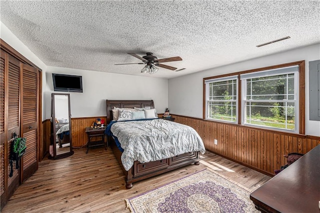 2518 Arrowhead Rd, Topeka, KS 66614 - bedroom featuring a wainscoted wall, wood finished floors, wooden walls, a textured ceiling, and a closet