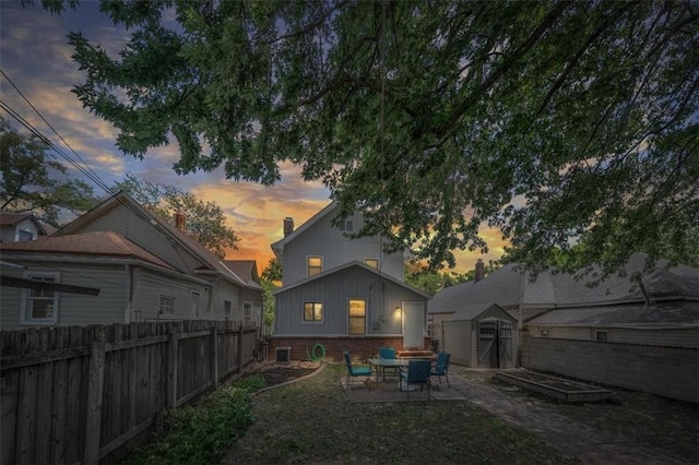 362 S 10th St, Kansas City, KS 66102 - back of property at dusk featuring a shed, brick siding, a patio area, and a fenced backyard