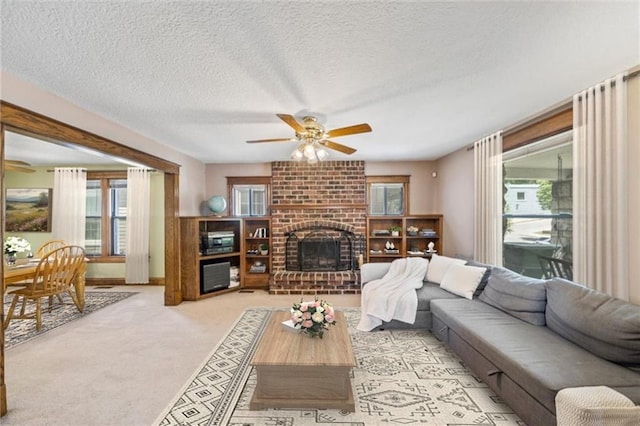 362 S 10th St, Kansas City, KS 66102 - living area featuring ceiling fan, a brick fireplace, a textured ceiling, and light colored carpet