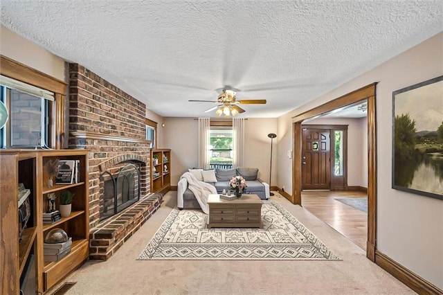 362 S 10th St, Kansas City, KS 66102 - living room featuring a brick fireplace, carpet, a ceiling fan, and a textured ceiling