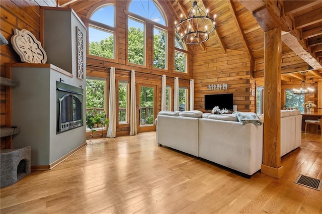 389 NW 1851st Rd, Kingsville, MO 64061 - living room with a chandelier, a stone fireplace, a wood ceiling with exposed beams, wooden walls, and high vaulted ceiling