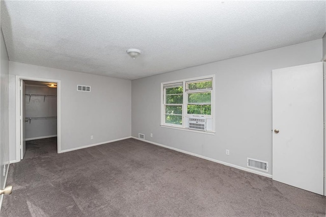 12731 Byars Rd, Grandview, MO 64030 - unfurnished bedroom featuring dark carpet, a textured ceiling, a spacious closet, and a closet