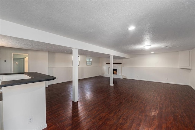 12731 Byars Rd, Grandview, MO 64030 - below grade area with wood finished floors, a textured ceiling, and a warm lit fireplace