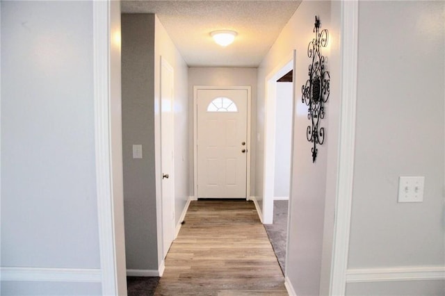 12731 Byars Rd, Grandview, MO 64030 - doorway to outside with wood finished floors and a textured ceiling