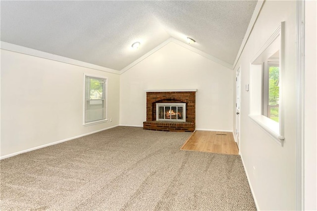 805 NW 18th St, Blue Springs, MO 64015 - unfurnished living room with carpet floors, healthy amount of natural light, vaulted ceiling, a fireplace, and a textured ceiling