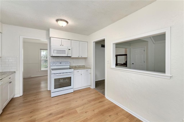 805 NW 18th St, Blue Springs, MO 64015 - kitchen featuring white appliances, decorative backsplash, white cabinets, light wood finished floors, and a textured ceiling