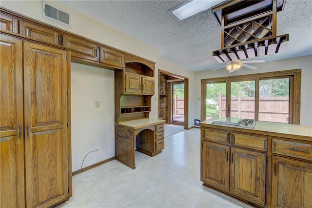 4008 NE 57th Ter, Kansas City, MO 64119 - kitchen with light flooring, brown cabinets, a textured ceiling, light countertops, and ceiling fan