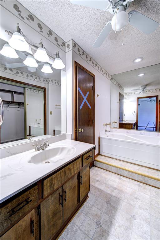 4008 NE 57th Ter, Kansas City, MO 64119 - full bath with a ceiling fan, a bath, vanity, and a textured ceiling