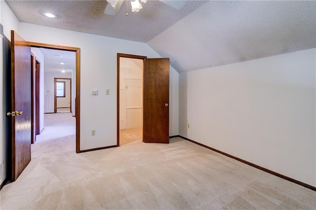 4008 NE 57th Ter, Kansas City, MO 64119 - unfurnished bedroom featuring light colored carpet, a textured ceiling, a walk in closet, vaulted ceiling, and a ceiling fan