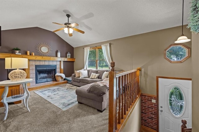 15509 Lawrence Ave, Belton, MO 64012 - living room featuring a ceiling fan, vaulted ceiling, a textured ceiling, carpet, and a tile fireplace
