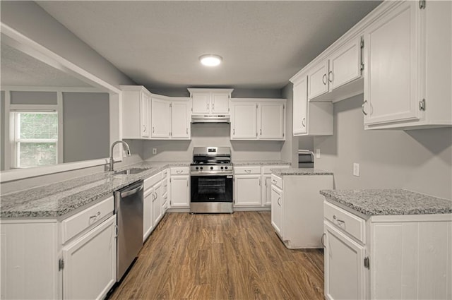 8167 NE 50th St, Kansas City, MO 64119 - kitchen featuring stainless steel appliances, wood finished floors, white cabinetry, light stone counters, and under cabinet range hood