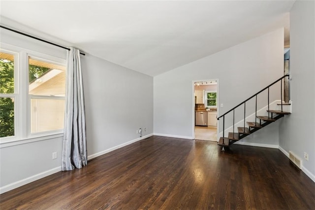 4112 N Hardesty Ave, Kansas City, MO 64117 - unfurnished living room featuring plenty of natural light, stairs, lofted ceiling, and wood finished floors