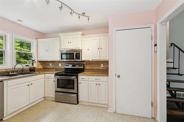 4112 N Hardesty Ave, Kansas City, MO 64117 - kitchen with stainless steel appliances, tasteful backsplash, white cabinetry, and light countertops