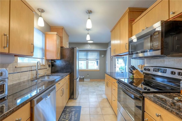 5101 NW Downing St, Blue Springs, MO 64015 - kitchen featuring stainless steel appliances, decorative backsplash, light tile patterned floors, and dark stone countertops