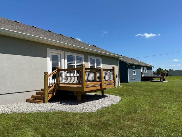 407 N Harmon St, Girard, KS 66743 - rear view of property featuring a wooden deck, stucco siding, and a lawn