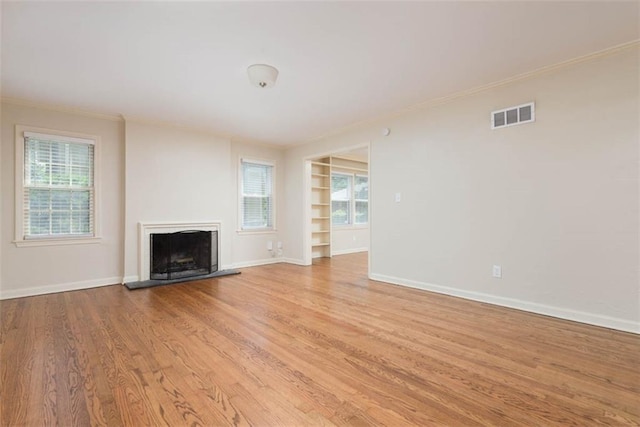 627 E Meyer Blvd, Kansas City, MO 64131 - unfurnished living room featuring light wood-style floors, built in shelves, ornamental molding, and a fireplace with raised hearth