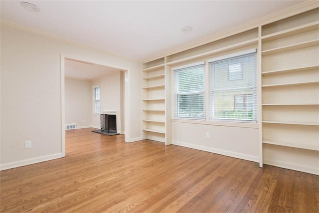627 E Meyer Blvd, Kansas City, MO 64131 - unfurnished living room featuring built in features, a fireplace with raised hearth, crown molding, wood finished floors, and plenty of natural light