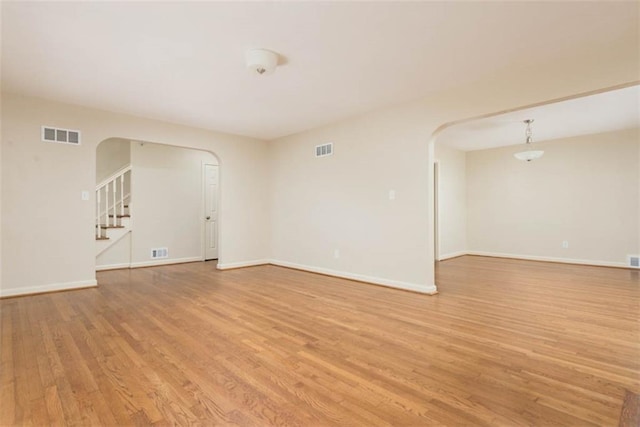 627 E Meyer Blvd, Kansas City, MO 64131 - unfurnished room featuring arched walkways, light wood-style flooring, and stairs