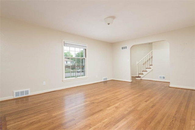 627 E Meyer Blvd, Kansas City, MO 64131 - spare room featuring light wood-type flooring, stairway, and arched walkways
