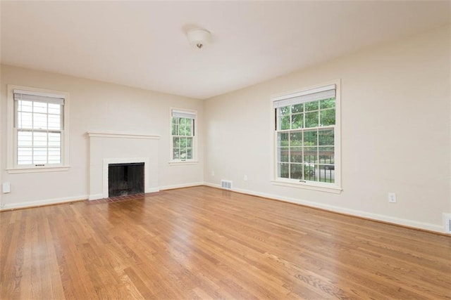 627 E Meyer Blvd, Kansas City, MO 64131 - unfurnished living room with light wood-style flooring, plenty of natural light, and a fireplace with flush hearth