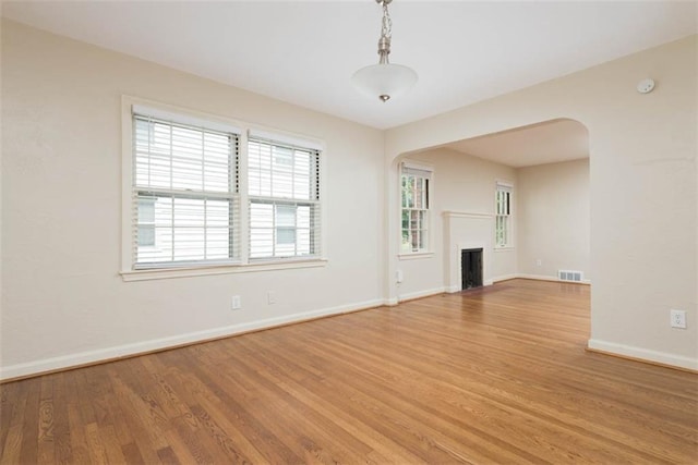627 E Meyer Blvd, Kansas City, MO 64131 - unfurnished living room with arched walkways, light wood finished floors, and a fireplace