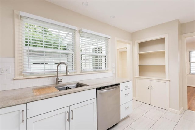 627 E Meyer Blvd, Kansas City, MO 64131 - kitchen with stainless steel dishwasher, light countertops, white cabinets, backsplash, and light tile patterned floors