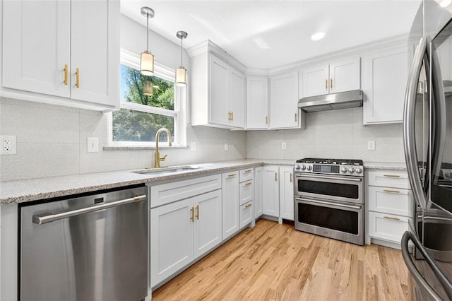 2623 W 131st St, Olathe, KS 66061 - kitchen featuring appliances with stainless steel finishes, under cabinet range hood, white cabinetry, light wood-style flooring, and decorative backsplash
