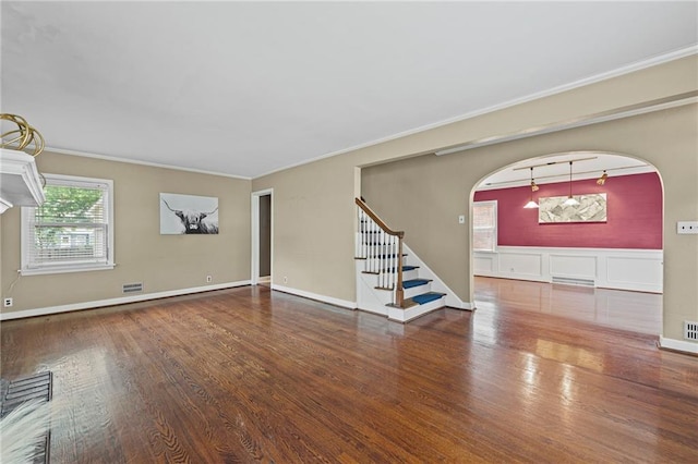 1296 W 72nd Ter, Kansas City, MO 64114 - unfurnished living room featuring wood finished floors, arched walkways, crown molding, and stairs