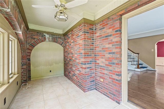 1296 W 72nd Ter, Kansas City, MO 64114 - corridor with brick wall, ornamental molding, stairway, tile patterned flooring, and arched walkways
