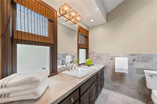 1296 W 72nd Ter, Kansas City, MO 64114 - bathroom with tile walls, double vanity, a wainscoted wall, tile patterned floors, and a chandelier