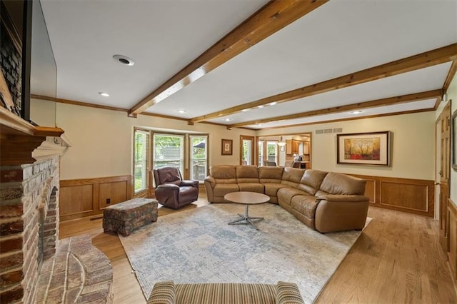 12147 Farley St, Overland Park, KS 66213 - living area featuring wainscoting, light wood-style floors, beamed ceiling, a fireplace with raised hearth, and ornamental molding