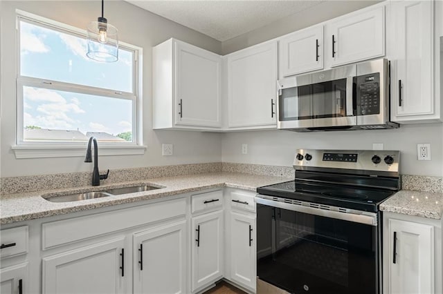 32625 W 174th St, Gardner, KS 66030 - kitchen with stainless steel appliances, white cabinetry, decorative light fixtures, light stone countertops, and a textured ceiling