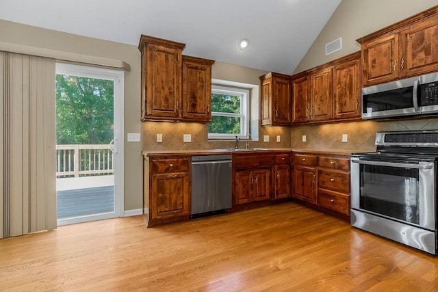 701 Tomahawk Ct, Smithville, MO 64089 - kitchen featuring appliances with stainless steel finishes, light wood finished floors, backsplash, and vaulted ceiling