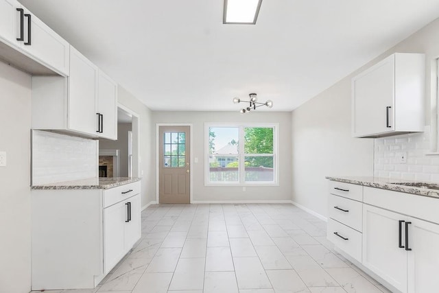 18201 W 157th Ter, Olathe, KS 66062 - kitchen featuring light marble finish floors, backsplash, light stone countertops, and white cabinets