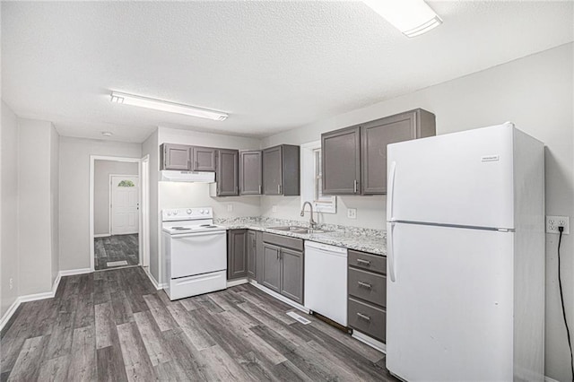 4937 Highland Ave, Kansas City, MO 64110 - kitchen with white appliances, under cabinet range hood, dark wood-style flooring, light countertops, and a textured ceiling