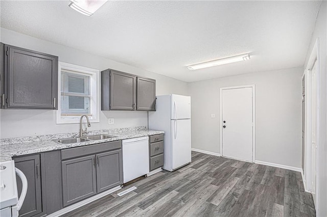 4937 Highland Ave, Kansas City, MO 64110 - kitchen featuring white appliances, dark wood-style flooring, a textured ceiling, gray cabinetry, and light stone counters