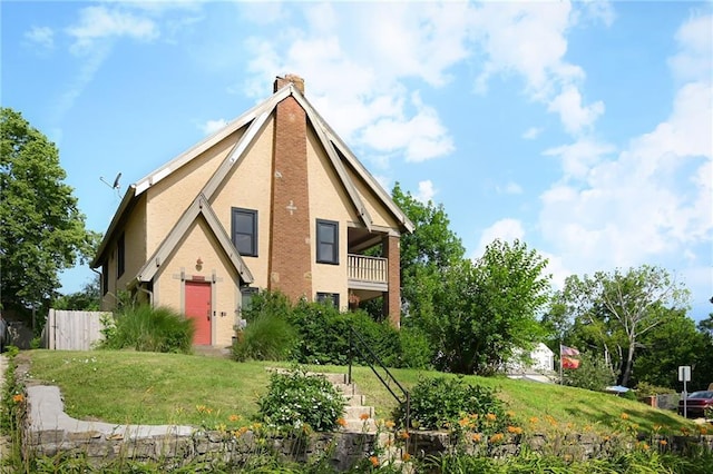 5024 Woodland Ave, Kansas City, MO 64110 - view of front facade with a balcony, a chimney, and stucco siding