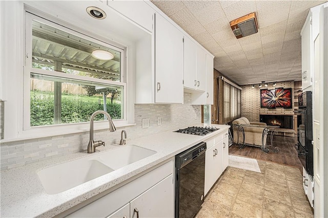 5919 N Adrian Ter, Kansas City, MO 64152 - kitchen featuring black appliances, white cabinets, a warming drawer, decorative backsplash, and a brick fireplace