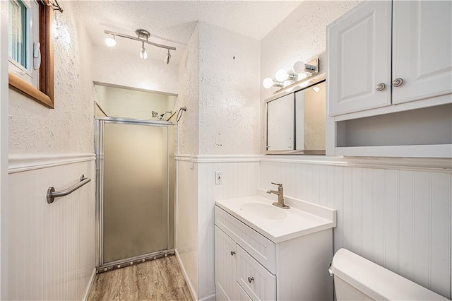 5919 N Adrian Ter, Kansas City, MO 64152 - full bathroom featuring a shower stall, wainscoting, vanity, wood finished floors, and a textured ceiling