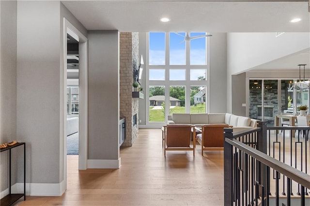 1113 Hummingbird Ct, Greenwood, MO 64034 - hallway featuring light wood-style flooring, a high ceiling, and a chandelier