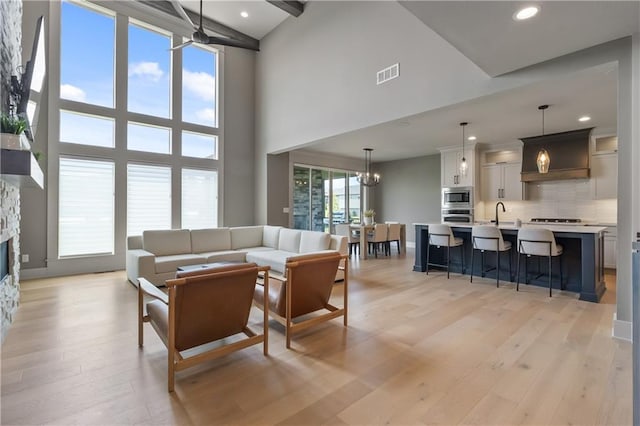 1113 Hummingbird Ct, Greenwood, MO 64034 - living room with a towering ceiling, a fireplace, light wood-style flooring, recessed lighting, and a chandelier